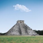 Historic Chichen Itza pyramid in Mexico against a bright blue sky with a solitary cloud.